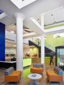 The two-story main entry lobby includes lounge spaces, a security check-in station, and vertical circulation.
