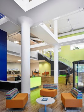 The two-story main entry lobby includes lounge spaces, a security check-in station, and vertical circulation.