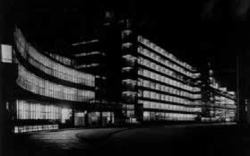 The staples of Modern Architecture—glass, steel, and concrete—made large glass expanses possible for buildings of the 1920s and 1930s. This allowed an abundance of daylight to permeate spaces by day, and by night the reverse effect, as internally electrically illuminated buildings cast their light back out into the urban realm. The Van Nelle Factories, Rotterdam, 1931, is one such example. A model is on display as part of the exhibition.