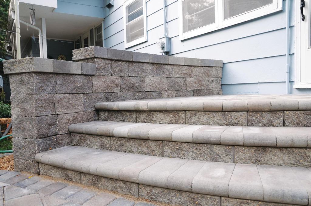 Versa-Lok top-pinning segmental retaining wall system is now available in a bronze blend color. The concrete system is finished in either a traditional split-face or a vintage weathered texture and readily accommodates soil reinforcement to build walls 50' or taller. It can be used to build walls, curves, multi-angle corners, stairs, and freestanding walls and columns. No specialty pieces are required, and no hollow cores are created to be filled. Versa-Lok is available in several options, including Standard, Cobble, Accent, random-pattern Mosaic, Mosette, Brute, Bronco, Square Foot, and Versa-Green (which is plantable). versa-lok.com