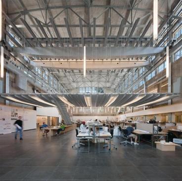 A stair linking the Crib to the floor below is supported on a single box girder that appears to peel down from the Crib?s floor system. The stair itself is a series of welded, bent steel plates, bracketed by a stainless steel railing and draped with steel mesh. Interior staircases lead from the studio level to offices and galleries above.