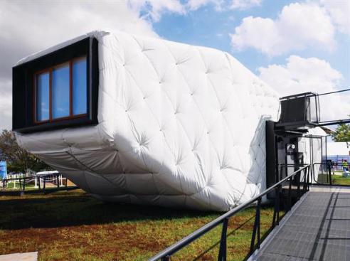 The house features an exterior skin made of 14 to 16 inches of denim batt insulation wrapped with a low-cost, engineered, vinyl-coated polyester fastened with zip ties, dowel rods, and lag screws.