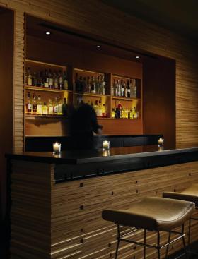 Black-painted steel detailing can be seen under the lip of the bar top. It provides a transition between the black granite counter and the milled Baltic birch of the bar face, and also incorporates hooks so that bags and briefcases can stay off the floor.
