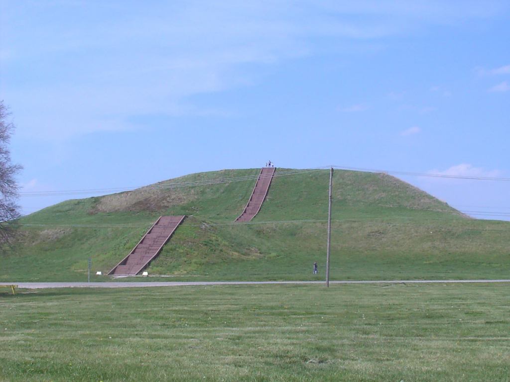 Monk's Mound, created by the Mississippian culture, is located at Cahokia. The staircase you see is new, but built to follow the course of the original wooden stairs. Also visible is a road and power lines cutting through the site.