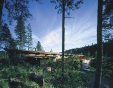 A long cedar porch blurs the houses southern edge, in contrast to the closed face on the north side, where cedar boxes contain the baths and pantry.