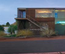 A lime green, laminated glass balcony supplies a bold contrast to the projects rusted steel siding.