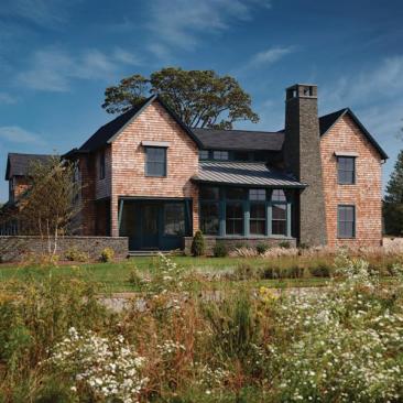 The architects responded to their clients  wish for a Saab like aesthetic with minimal detailing and subdued materials  weathered red cedar shingles, bluestone, and painted aluminum standing seam roofing.