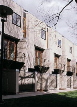 Steel balconies, wood windows and doors, and color-through black stucco establish a rhythm on the facade.