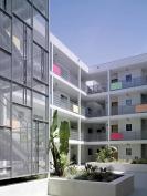 Details such as the stair's perforated-metal screen, brown-painted aluminum louvers, and colorful balconies contribute low-cost luxury. The only splurge was a commercial storefront system with operable windows.