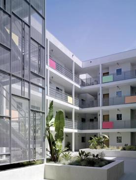 Details such as the stair's perforated-metal screen, brown-painted aluminum louvers, and colorful balconies contribute low-cost luxury. The only splurge was a commercial storefront system with operable windows.