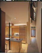 The elegant rear facade combines Kalwall and fixed glass, and steel windows and doors. Concrete and rustedsteel form the fireplace wall. A simple curve in the plan creates a light well in the narrow house.