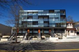 The four street-level duplexes feature glassy facades open to front yards and stoops, like the surrounding row houses. Each of the 26 units has a different layout, with flats on the second and third floors, and four penthouses on top.