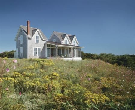 The low-slung massing that ties the house together starts at the front entry, encapsulates the interior public spaces, and then goes back outside to protect a screened porch and open terrace along the rear water-facing elevation (shown here).