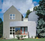 Traditional stucco and clapboard cladding coexist with a copper brise-soleil, which minimizes the house's scale and reflects light in interesting ways.