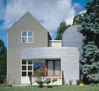 Traditional stucco and clapboard cladding coexist with a copper brise-soleil, which minimizes the house's scale and reflects light in interesting ways.