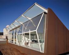 A floating staircase, with triangulated treads for strength, rises from the ground-floor office to a transparent penthouse and deck.