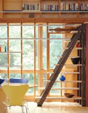 The alternating tread staircase, made from oak and maple, attaches to the side of a built-in refrigerator. It comes in handy as a way to reach cookbooks, which are shelved on the kitchen side of the loft space.