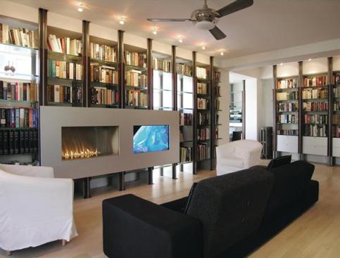 Anchored at floor and ceiling, the living room shelving unit supports a gas fireplace and flat-screen TV housed in the same aluminum surround