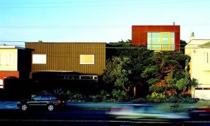 The addition (right side of image) nestles into the lush landscaping around the existing house (left side).