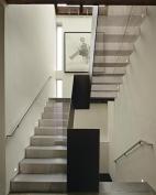 Stair runs fabricated from folded sheets of perforated steel filter light from a skylight above.