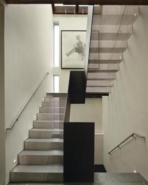 Stair runs fabricated from folded sheets of perforated steel filter light from a skylight above.
