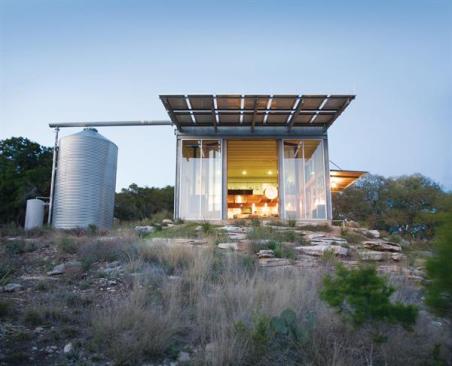 Big glass doors and an overhang of solar panels make up the guesthouse's front elevation.