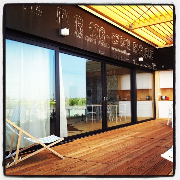 The Air House's back porch sits beneath a second skin of fixed wooden louvers that shade the dwelling unit and its small exterior space.