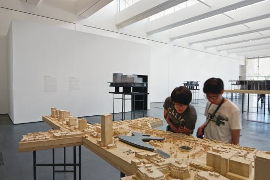 Visitors at LACMA’s Resnick Exhibition Pavilion survey Peter Zumthor’s proposed model for the museum campus.