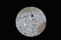 Sampled from ancient Roman maritime concrete near Naples, Italy, this 9-centimeter-diameter drill core comprises lime (white spots), lava (dark fragments), pumice (yellowish inclusions), volcanic ash, and other volcanic crystalline materials.
