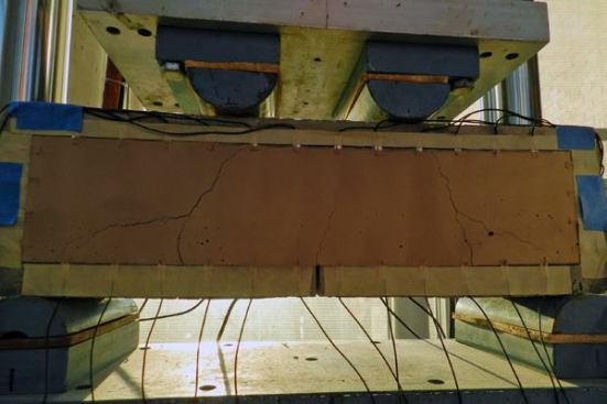 A notched beam undergoes a four-point bending test, which causes its surface to crack.