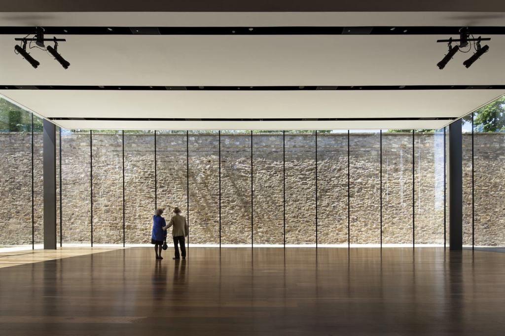 A former prison wall serves as a rugged backdrop for the streamlined events space.