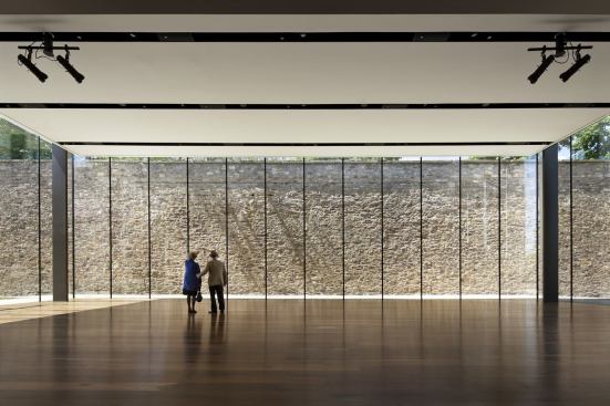 A former prison wall serves as a rugged backdrop for the streamlined events space.