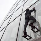 Elliot Hawkes, a mechanical engineering graduate student at Stanford University, scales the exterior of a glass wall using adhesive grips.