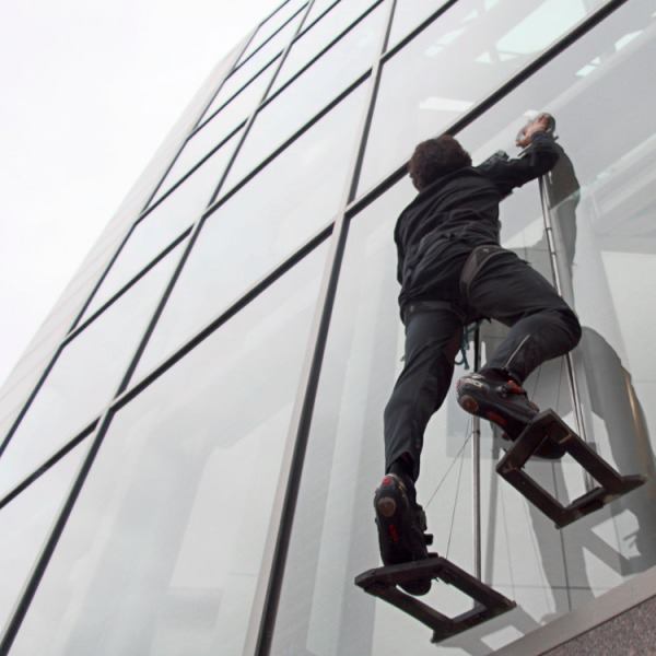 Elliot Hawkes, a mechanical engineering graduate student at Stanford University, scales the exterior of a glass wall using adhesive grips.