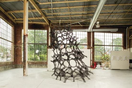 Area sculpted the 14-foot-tall, 8-foot-wide, and 31-pound C-Lith installation from carbon fiber pre-impregnated with epoxy resin. The structure’s form was derived from a packed tetrahedral base geometry.