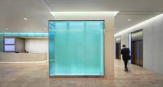 A backlit, glass-walled corner guides building patrons to the elevator bank.