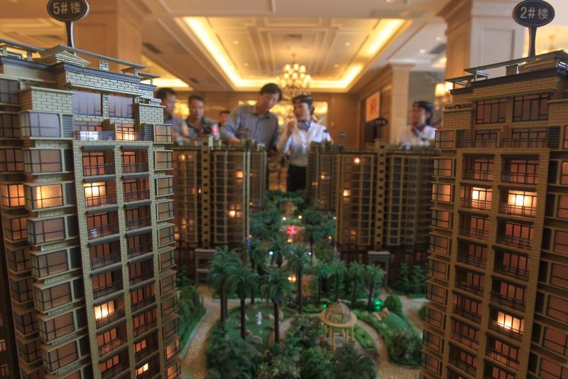 Chinese homebuyers look at models of apartment buildings during a real estate fair in Haikou City in China's Hainan province on Nov. 29. According to a recent survey, China's housing prices fell on a monthly basis for the seventh straight month in November, with the market yet to feel the full impact of an interest rate cut. The average price of a new home in China's 100 major cities was 10,589 yuan ($1,736) per square metre in November, down 0.38 percent from October, according to the China Index Academy.