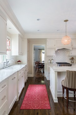 View past sink in beautiful white kitchen into dining room