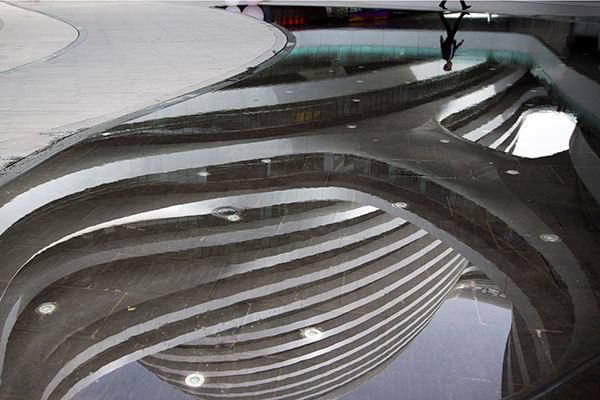 A man's reflection as he walks past the Galaxy Soho on May 15. Zaha Hadid, Hon. FAIA, designed the building in Beijing, China.