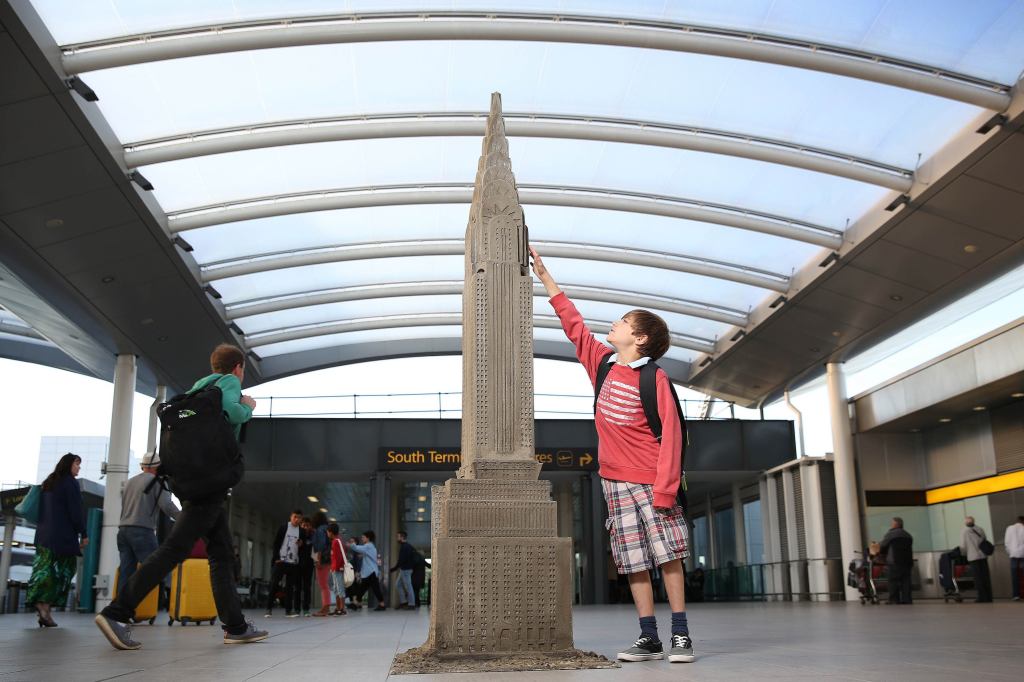 Nine-year-old Theo Mackintosh with a sculpture of the Chrysler Building built with sand, wood, and cement. The sculpture is one of two currently on display by London artist Dean Zeus Coleman at the city's Gatwick Airport. (The other is of the Burj Al Arab.) The installations were commissioned to recognize new flights to New York City and Dubai.