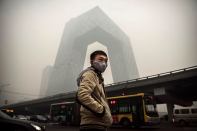 A man wears a mask during heavy smog in Beijing last month. OMA's CCTV building stands in the background.