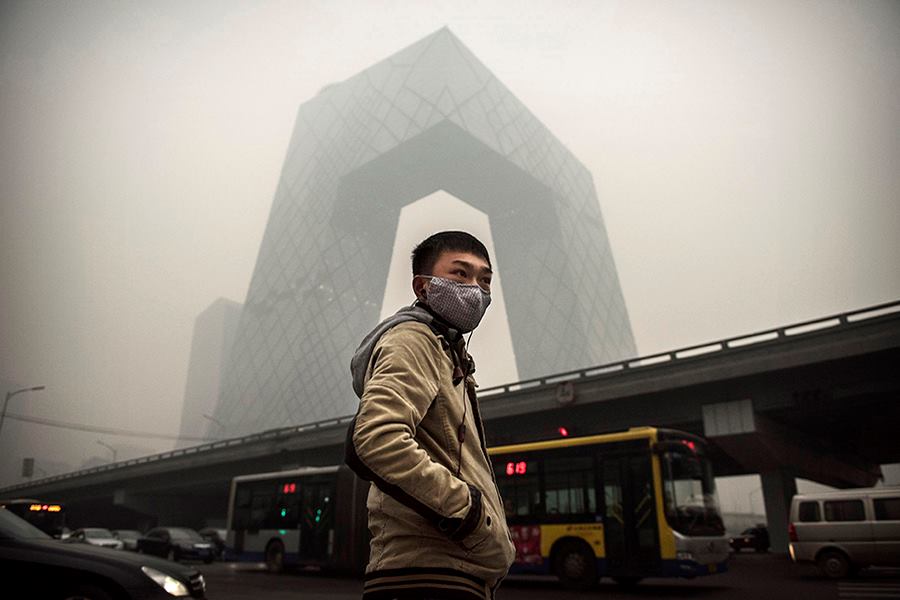 A man wears a mask during heavy smog in Beijing last month. OMA's CCTV building stands in the background.