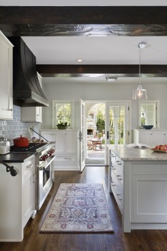 High end kitchen showing stove and view outside french doors to beautiful outdoor space