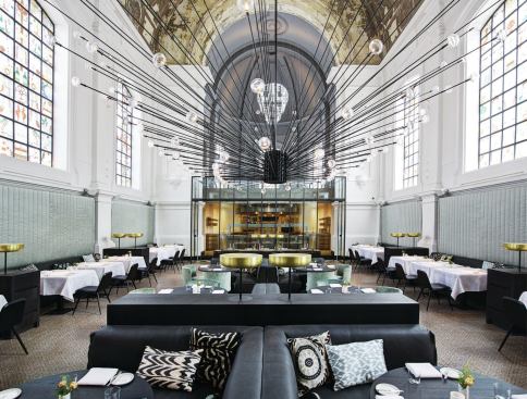 A view of the restaurant's main dining area with its lighting focal point: a custom chandelier-like installation that fills the center of the space.