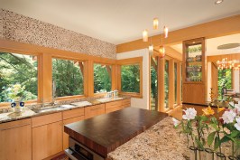 Nestled
  away adjacent to a lake, this lakeside residence is an example of fixed
  rusticity. The bright oak finish glows in comparison to the lush green forest
  beyond, creating a certain brightness throughout the home.