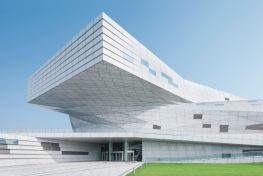 Emerging from the low-slung, knot-like form of the museum, a large prismatic cantilever on the south façade marks the entrance.