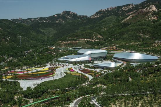 The buildings’ metal fins create a texture akin to paper parasols and conceal on their undersides a bright spectrum of color that unfolds around each structure.