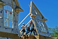 Workers push a second-floor, preframed dimension wood exterior wall frame up into position in Ann Arbor, Michigan.