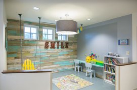 Play area with a LEGO wall and suspended Adirondack swing chair that is easy to view for parents.