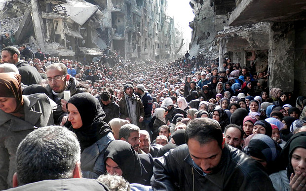Palestinian refugees queue for food and supplies in Damascus, Syria, in January 2014